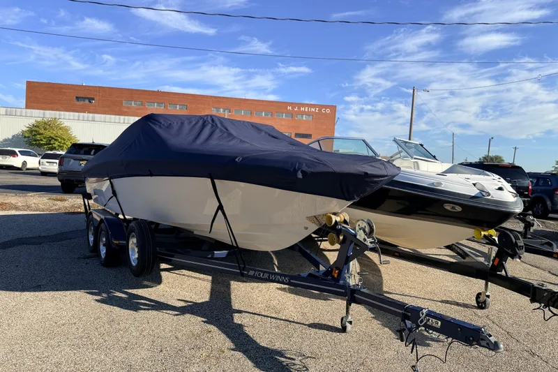 Slide: The Image of 2004 Four Winns 210 Horizon boat covered on trailer, parked outdoors. - 12