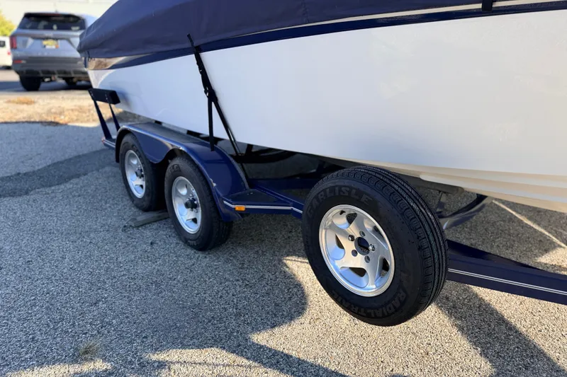Slide: The Image of 2004 Four Winns 210 Horizon boat on a dual-axle trailer, covered and parked. - 14