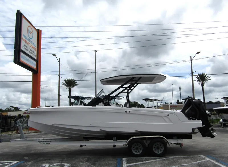 Slide: The Image of 2022 Axopar 22 T-Top boat on trailer at dealership, cloudy sky background. - 0