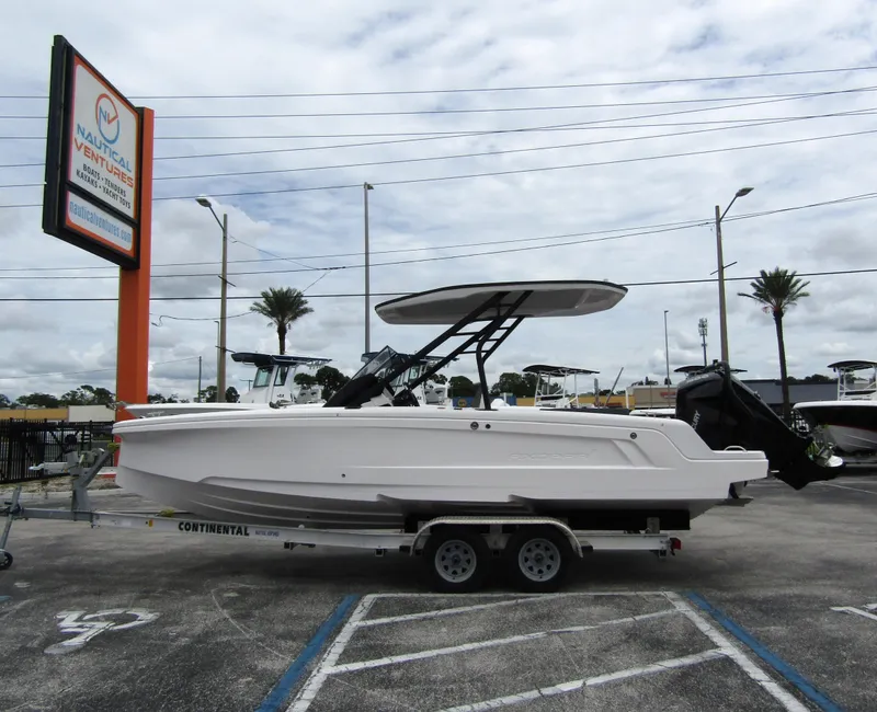 Slide: The Image of 2022 Axopar 22 T-Top boat on trailer in parking lot, cloudy sky background. - 0