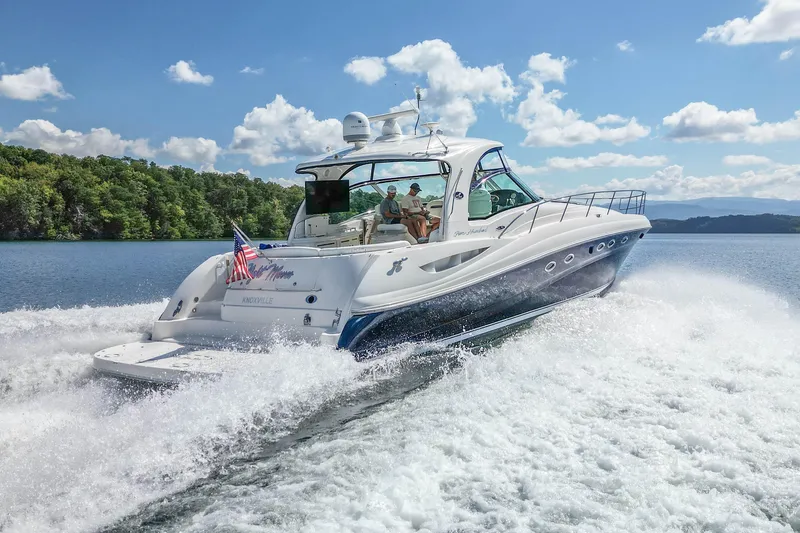 Slide: The Image of 2005 Sea Ray 500 Sundancer yacht cruising on a scenic lake under a clear blue sky. - 14