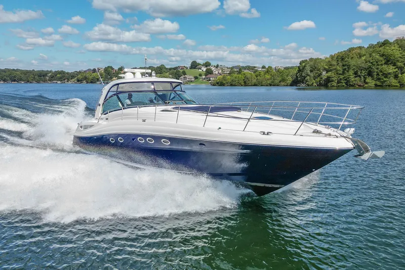 Slide: The Image of 2005 Sea Ray 500 Sundancer cruising on a scenic lake under a clear blue sky. - 16