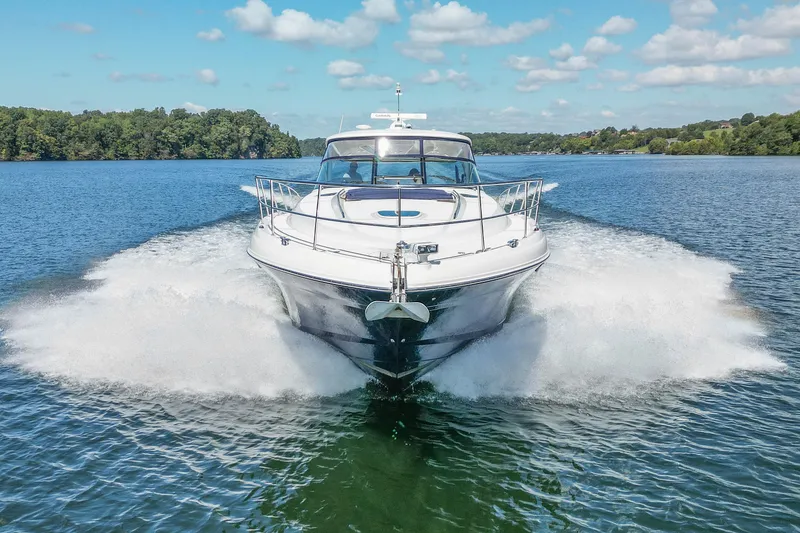 Slide: The Image of 2005 Sea Ray 500 Sundancer cruising on a serene lake under a clear blue sky. - 17