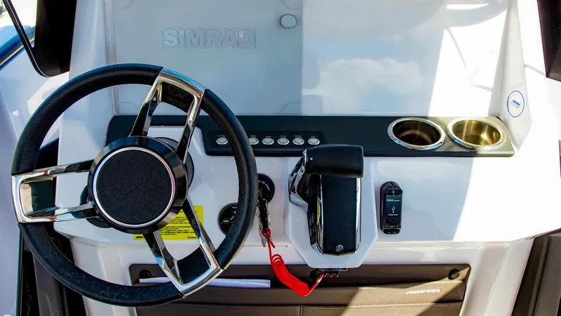 Slide: The Image of Steering console of 2023 Axopar 22 T-Top with modern controls and cup holders. - 5