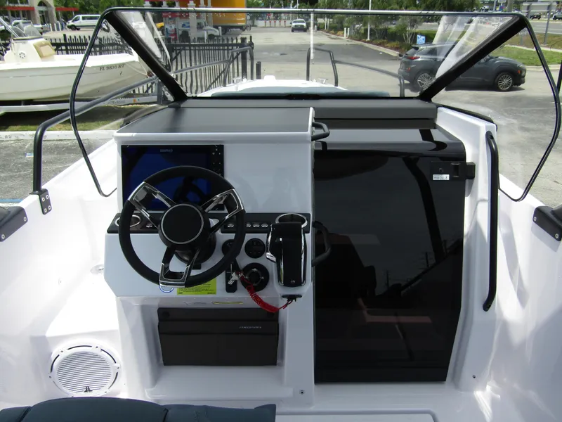 Slide: The Image of 2024 Axopar 25 Cross Top boat cockpit with steering wheel and control panel. - 13
