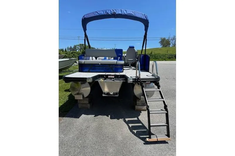 Slide: The Image of 2026 Bennington 23 SSB Swing Back Pontoon with blue canopy and ladder, parked on pavement. - 5