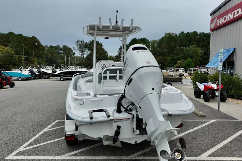 Slide: The Image of 2026 ALK2 23 CRX boat with powerful outboard motor in dealership parking lot. - 2