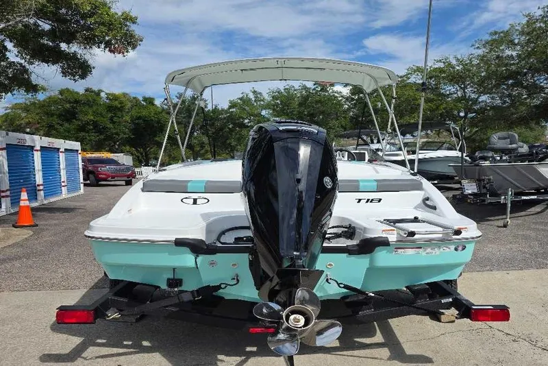 Slide: The Image of 2026 Tahoe T18 boat with canopy, docked outdoors under clear blue sky. - 3