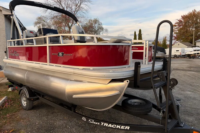 Slide: The Image of 2026 Sun Tracker Bass Buggy 16 XL Select pontoon boat on trailer, red and silver design. - 81