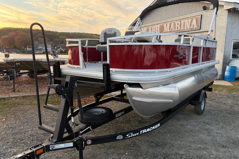 Slide: The Image of 2026 Sun Tracker Bass Buggy 16 XL Select pontoon boat on trailer at marina. - 82