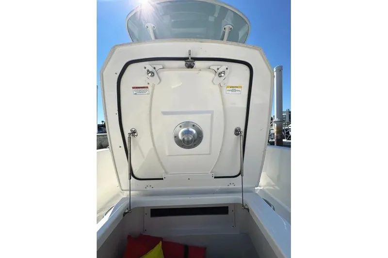 Slide: The Image of 2022 Boston Whaler 220 Dauntless boat storage compartment with open hatch under clear sky. - 19