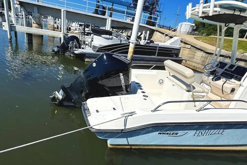 Slide: The Image of 2022 Boston Whaler 220 Dauntless boat docked, featuring Mercury outboard engine. - 2