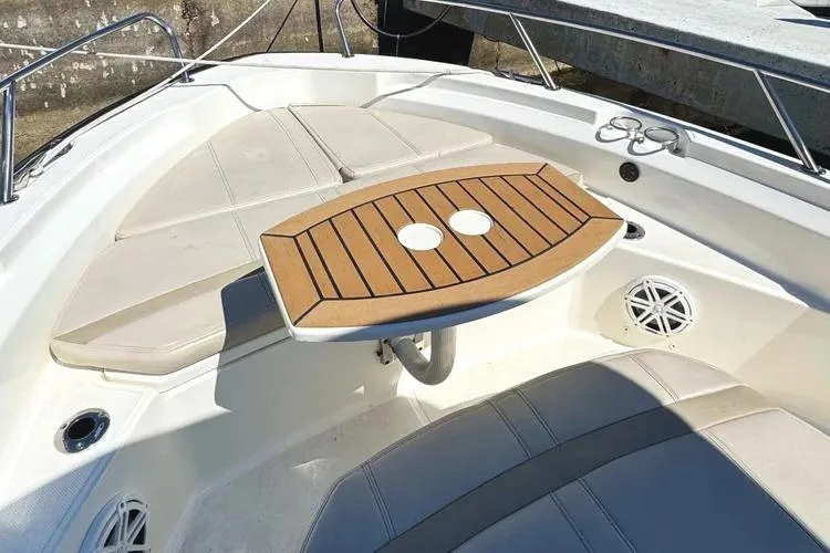 Slide: The Image of 2022 Boston Whaler 220 Dauntless boat interior with cushioned seating and wooden table. - 24