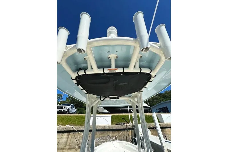 Slide: The Image of 2022 Boston Whaler 220 Dauntless boat with rod holders and T-top under clear sky. - 6