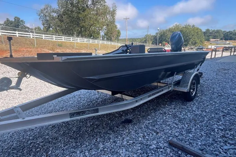Slide: The Image of Custom 1660 PF boat on trailer, 2026 model, parked on gravel with trees in background. - 2