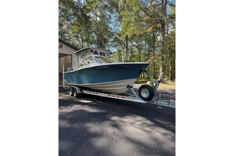 Slide: The Image of 2021 Grady-White Freedom 275 boat on trailer, parked outdoors near trees. - 0