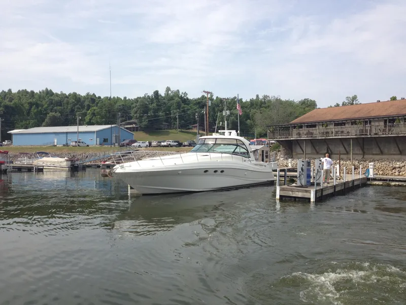 Slide: The Image of 2004 Sea Ray 500 Sundancer yacht docked at a marina with surrounding buildings and trees. - 2