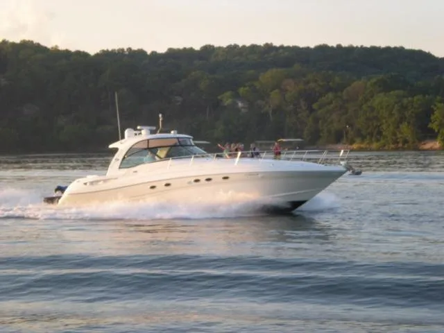 Slide: The Image of 2004 Sea Ray 500 Sundancer cruising on a serene lake with lush green shoreline. - 26