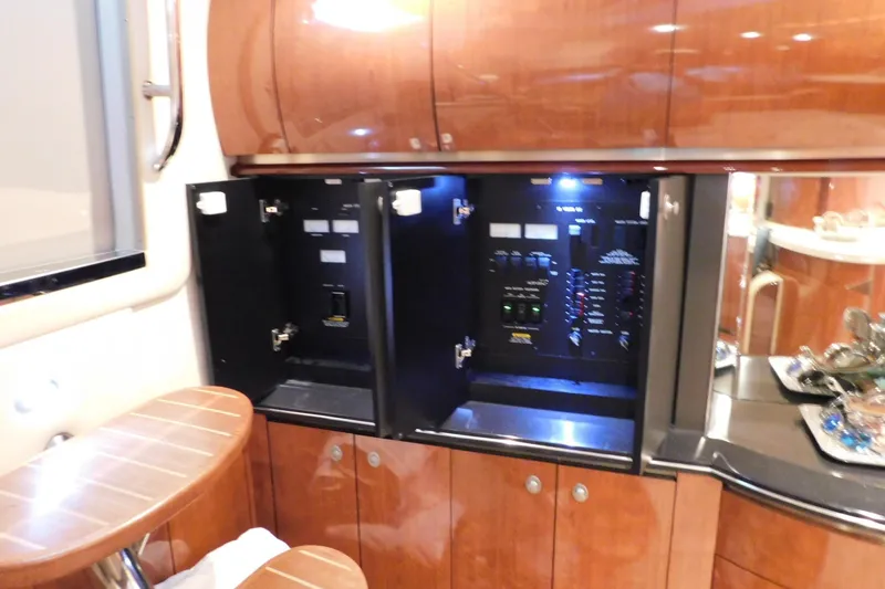 Slide: The Image of 2004 Sea Ray 500 Sundancer interior with open electrical panel and wooden cabinetry. - 32