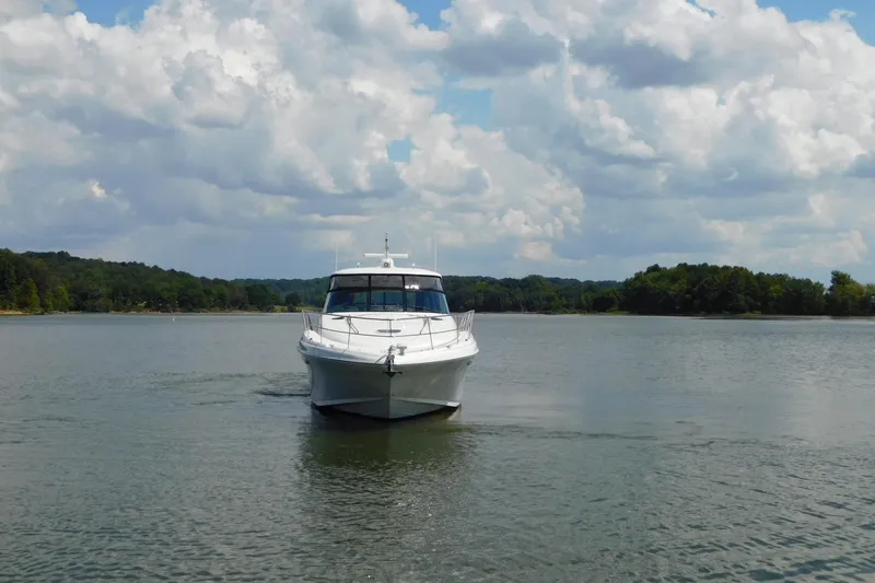 Slide: The Image of 2004 Sea Ray 500 Sundancer yacht cruising on a serene lake under a cloudy sky. - 51