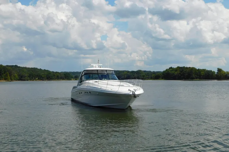Slide: The Image of 2004 Sea Ray 500 Sundancer yacht cruising on a serene lake under a cloudy sky. - 74
