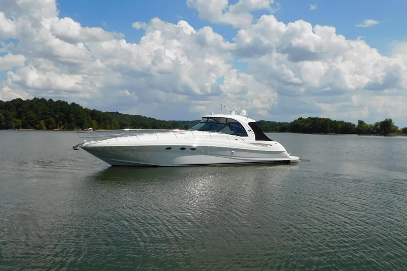 Slide: The Image of 2004 Sea Ray 500 Sundancer yacht cruising on a serene lake under a cloudy sky. - 75