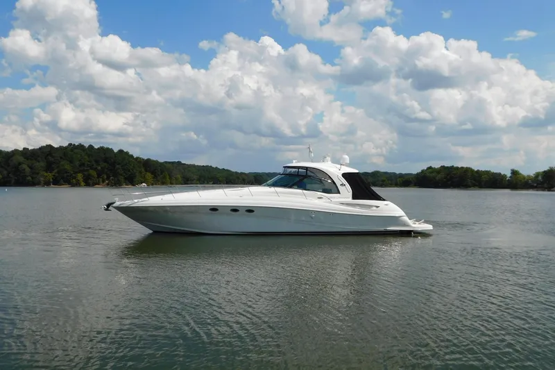 Slide: The Image of 2004 Sea Ray 500 Sundancer yacht on a serene lake under a cloudy sky. - 76
