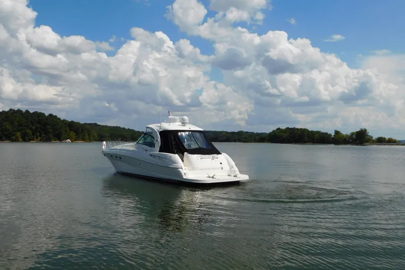 Slide: The Image of 2004 Sea Ray 500 Sundancer yacht cruising on a serene lake under a cloudy sky. - 79