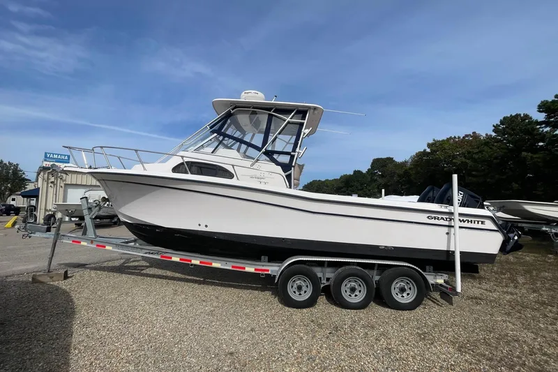 The Image of 2001 Grady-White Sailfish 255 boat on trailer, parked outdoors under clear sky. - 0