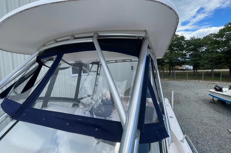 Slide: The Image of 2001 Grady-White Sailfish 255 boat with blue canopy and metal frame, parked outdoors. - 14