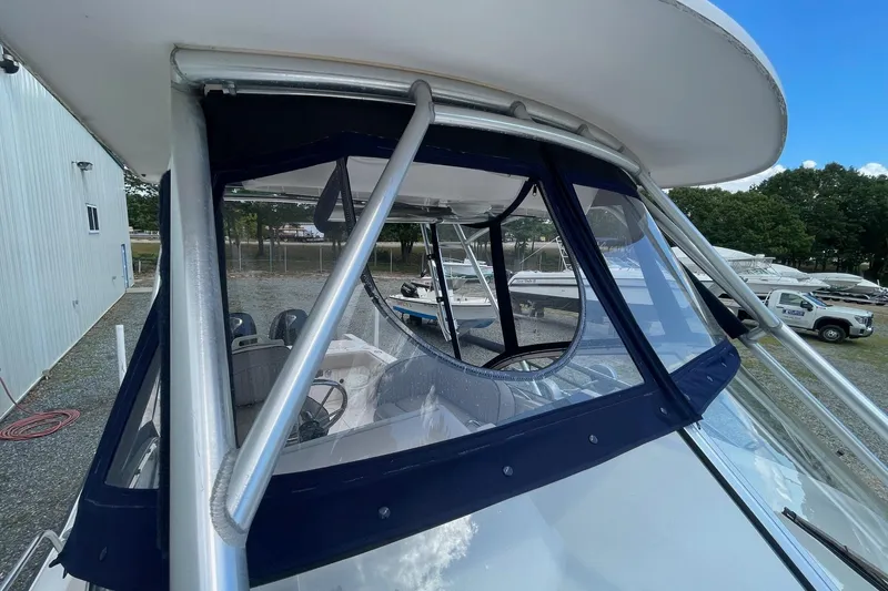 Slide: The Image of 2001 Grady-White Sailfish 255 boat with blue canvas enclosure and visible steering area. - 15