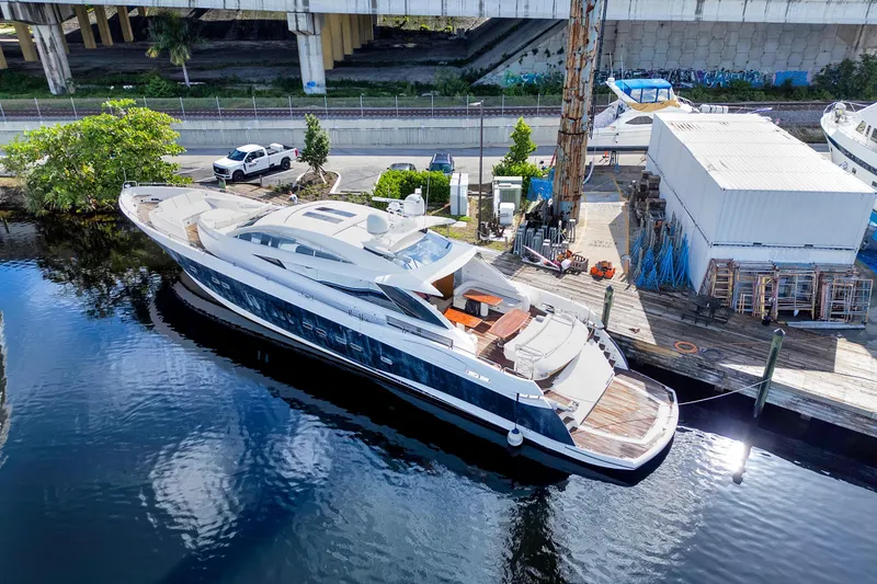 Slide: The Image of Sunseeker Predator 108 yacht, 2007 model, docked by a waterfront with nearby vehicles. - 1