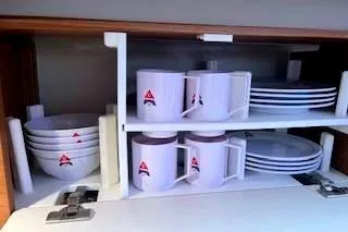 Slide: The Image of Cabinet with neatly stacked white dishes and mugs on a Catalina 445, 2016 model. - 31
