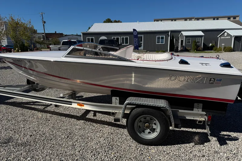 Slide: The Image of 2001 Donzi 16 Classic boat on trailer, parked on gravel, with building in background. - 4