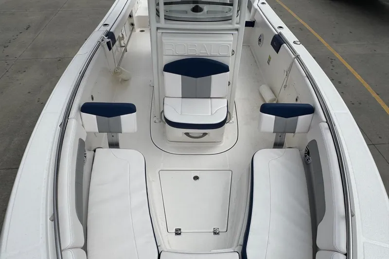 Slide: The Image of 2021 Robalo R242 Explorer boat interior with white and blue seating, docked on concrete. - 12