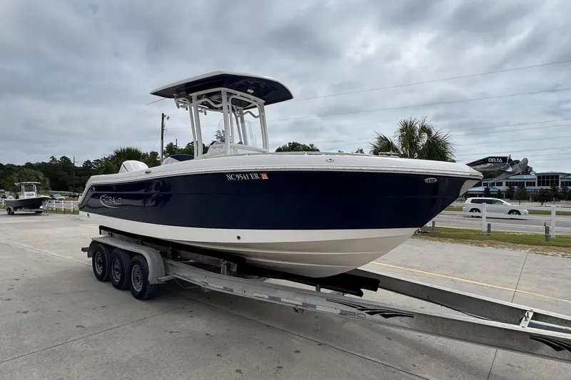 Slide: The Image of 2021 Robalo R242 Explorer boat on trailer, parked outdoors under cloudy sky. - 6