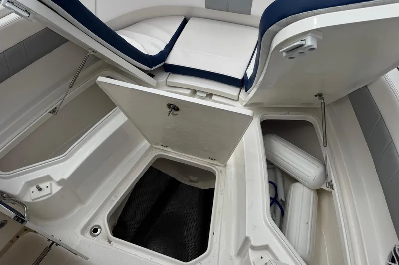 Slide: The Image of 2021 Robalo R242 Explorer boat storage compartments with open hatches and visible fenders. - 8
