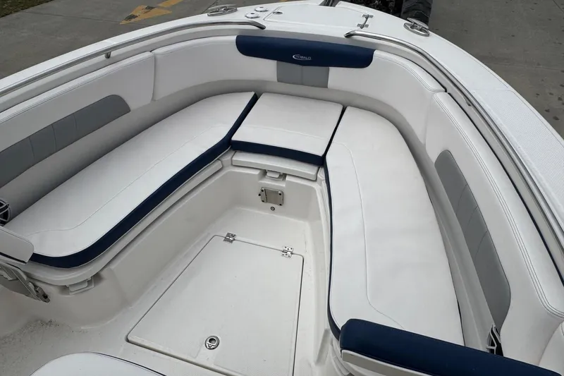 Slide: The Image of 2021 Robalo R242 Explorer boat interior with white cushioned seating and storage compartments. - 9
