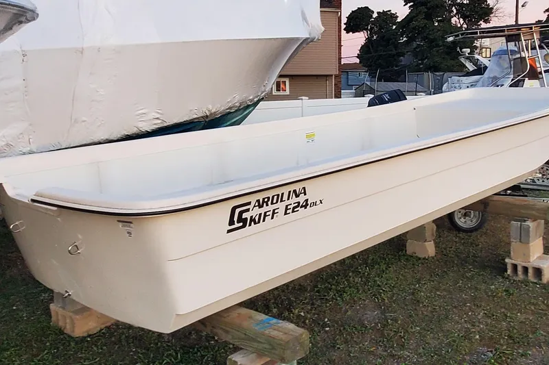 Slide: The Image of 2024 Carolina Skiff E24DLX Kit boat on display, resting on wooden blocks. - 3