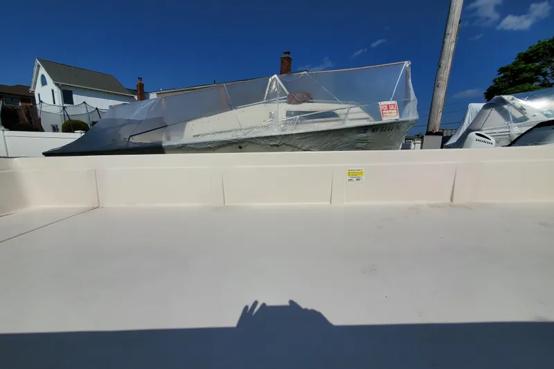 Slide: The Image of 2024 Carolina Skiff E24DLX Kit boat, covered and for sale, in a residential area. - 5