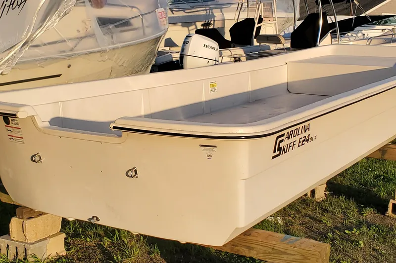 Slide: The Image of 2024 Carolina Skiff E24DLX Kit boat displayed on wooden supports outdoors. - 6