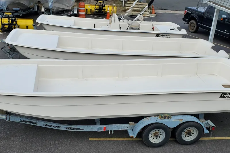 Slide: The Image of 2024 Carolina Skiff E24DLX Kit boats on trailers in a parking lot. - 7