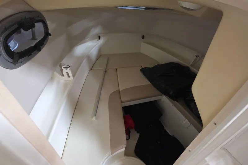 Slide: The Image of 2006 Boston Whaler 205 Conquest cabin interior with cushioned seating and storage space. - 10