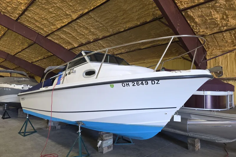Slide: The Image of 2006 Boston Whaler 205 Conquest boat in storage, white hull with blue bottom. - 12