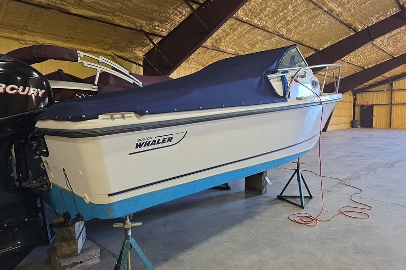 Slide: The Image of 2006 Boston Whaler 205 Conquest boat in storage, covered and elevated on stands. - 13