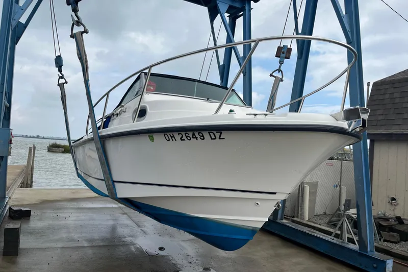 Slide: The Image of 2006 Boston Whaler 205 Conquest boat suspended on a lift near the water. - 4