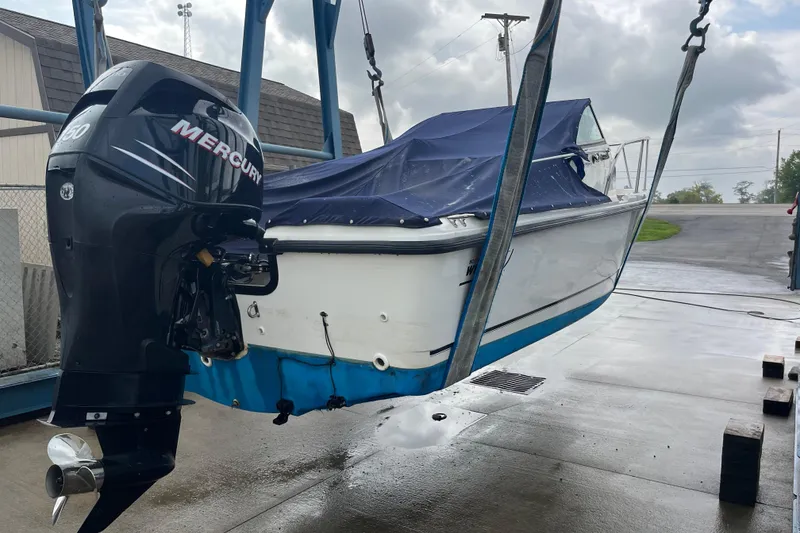 Slide: The Image of 2006 Boston Whaler 205 Conquest boat with Mercury engine, suspended on a lift. - 5