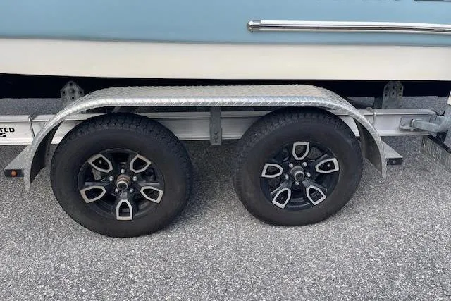 Slide: The Image of 2022 Pioneer 202 Islander boat trailer with dual black wheels on asphalt. - 26