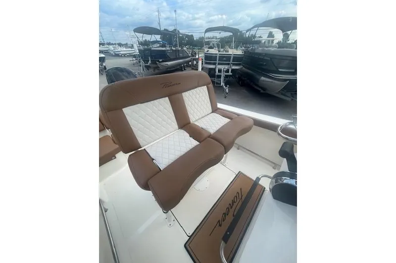 Slide: The Image of 2022 Pioneer 202 Islander boat with brown and white cushioned seating, docked near other boats. - 9