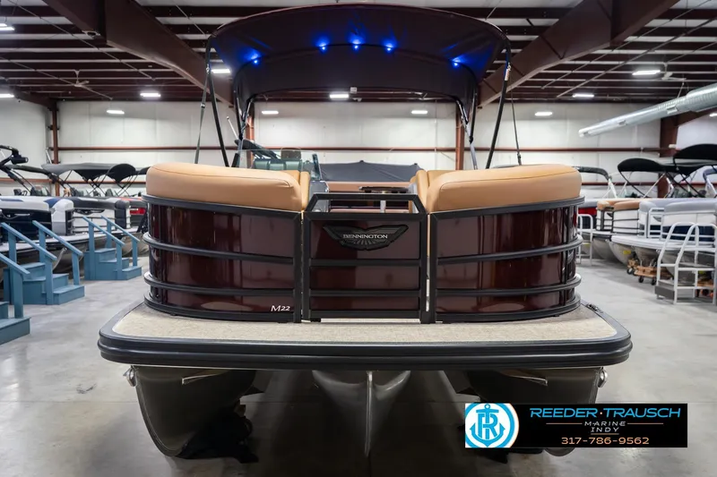 Slide: The Image of 2026 Bennington 22 ML pontoon boat in showroom, featuring tan seating and blue LED lights. - 5